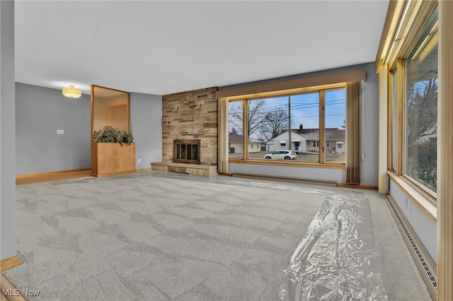 unfurnished living room with carpet floors, baseboards, a fireplace, and a baseboard heating unit