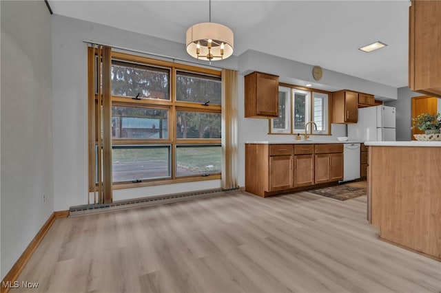 kitchen with light countertops, white appliances, light wood-style flooring, and brown cabinets