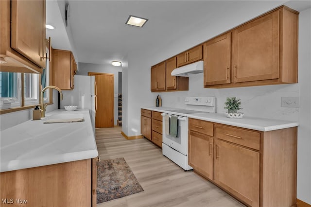 kitchen featuring white range with electric cooktop, light countertops, a sink, light wood-type flooring, and under cabinet range hood