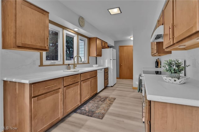 kitchen with light wood finished floors, light countertops, a sink, white appliances, and under cabinet range hood