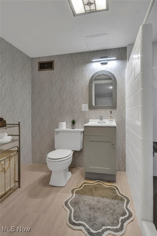 bathroom with visible vents, wood finished floors, vanity, and toilet