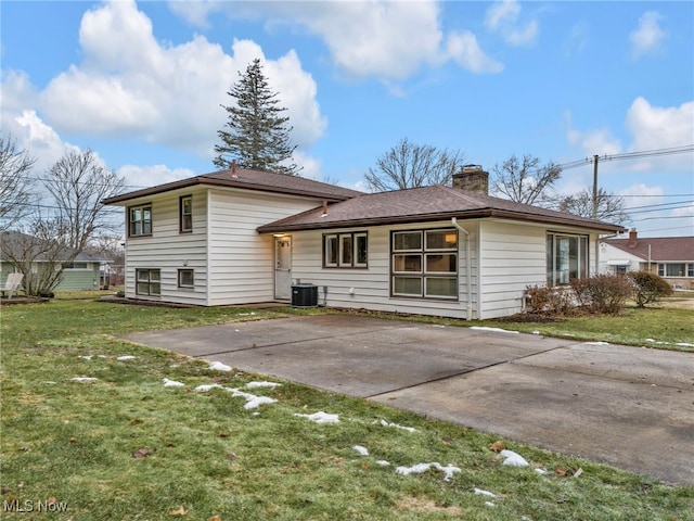 rear view of property with a patio area, a yard, a chimney, and central AC unit