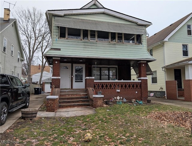 view of front of house with a porch, an outbuilding, and brick siding