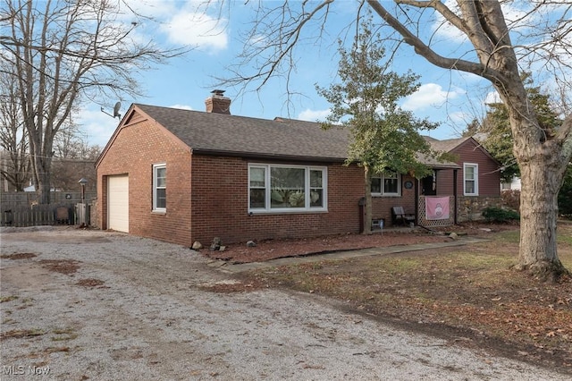 single story home featuring driveway, brick siding, a chimney, and roof with shingles