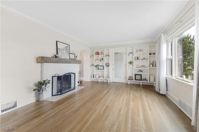 unfurnished living room featuring light wood finished floors, baseboards, a fireplace, and visible vents