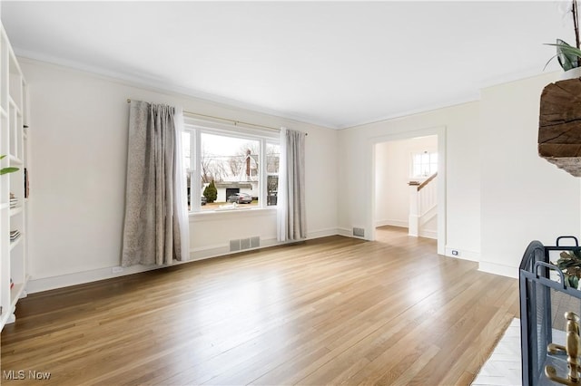 unfurnished living room featuring light wood finished floors, visible vents, stairs, and baseboards