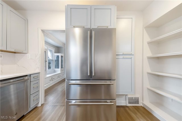 kitchen with stainless steel appliances, visible vents, backsplash, open shelves, and light wood finished floors