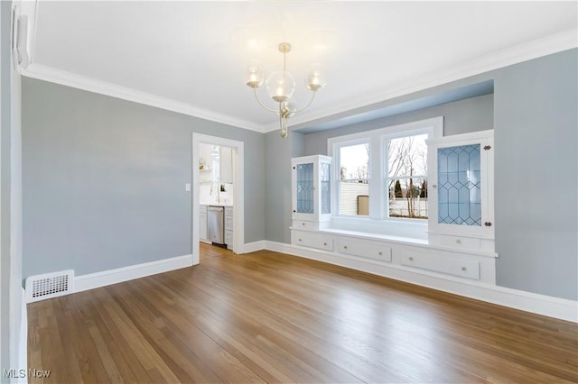 interior space featuring crown molding, visible vents, wood finished floors, a chandelier, and baseboards