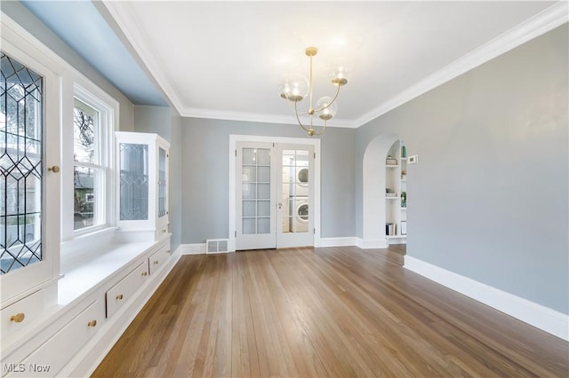 interior space with baseboards, visible vents, stacked washing maching and dryer, and wood finished floors