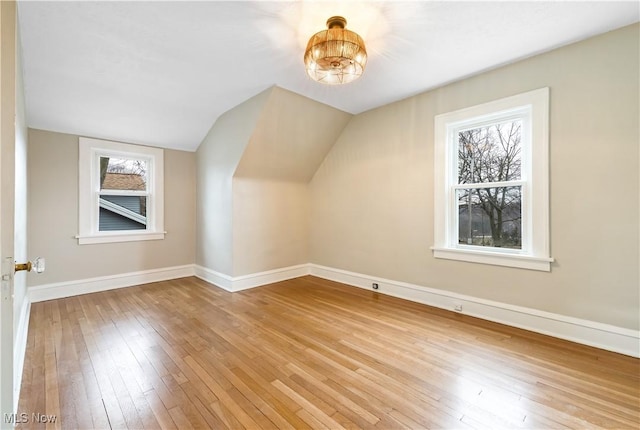 additional living space featuring vaulted ceiling, wood-type flooring, and baseboards