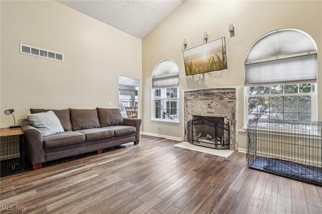 living room with a wealth of natural light, visible vents, a fireplace, and wood finished floors