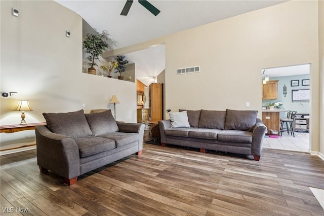 living room with ceiling fan, high vaulted ceiling, wood finished floors, and visible vents