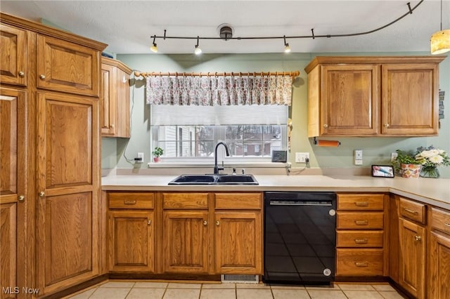 kitchen with black dishwasher, brown cabinets, a sink, and light countertops