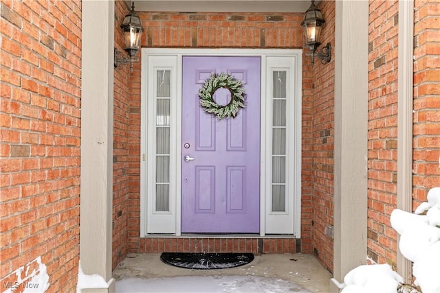 view of exterior entry featuring a porch and brick siding