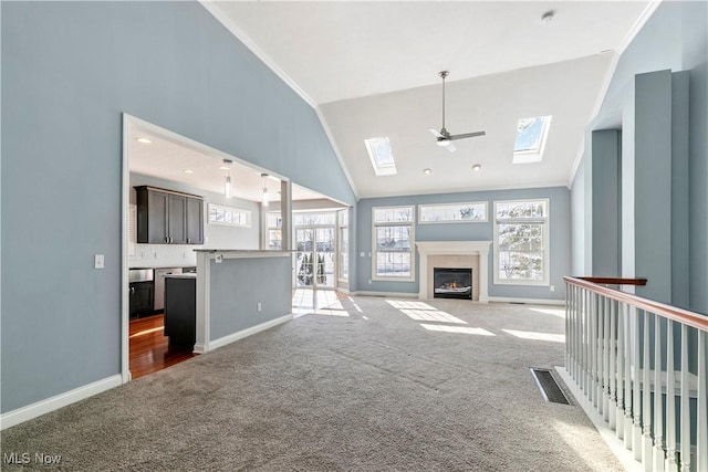 unfurnished living room featuring ornamental molding, a wealth of natural light, visible vents, and carpet