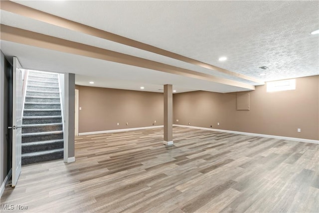 basement with baseboards, light wood-style flooring, stairway, a textured ceiling, and recessed lighting