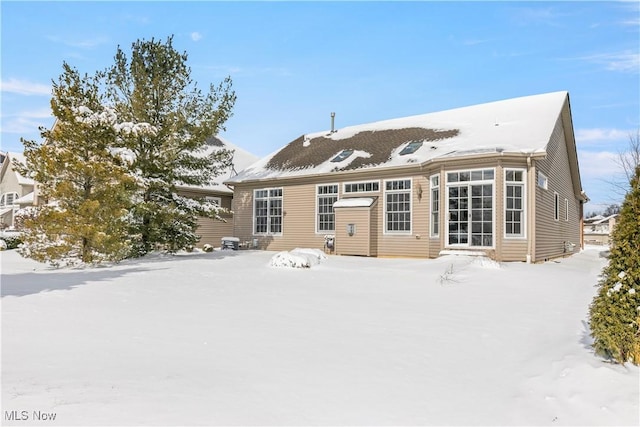 snow covered back of property featuring entry steps