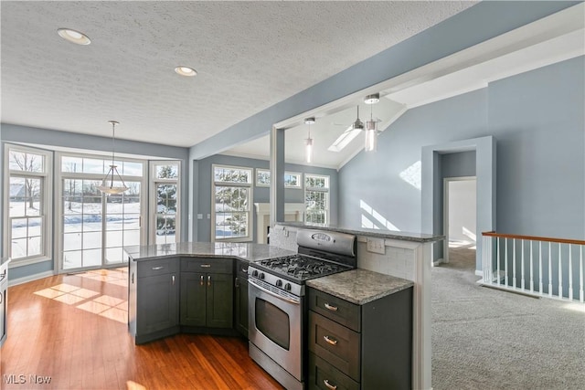 kitchen with stone counters, pendant lighting, stainless steel range with gas stovetop, vaulted ceiling, and wood finished floors