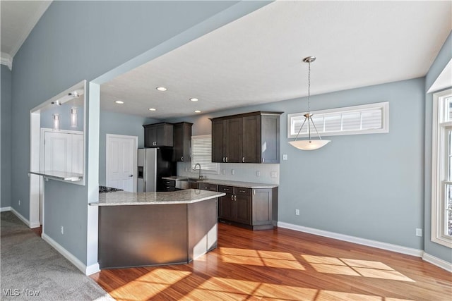 kitchen with baseboards, dark brown cabinetry, and stainless steel fridge with ice dispenser