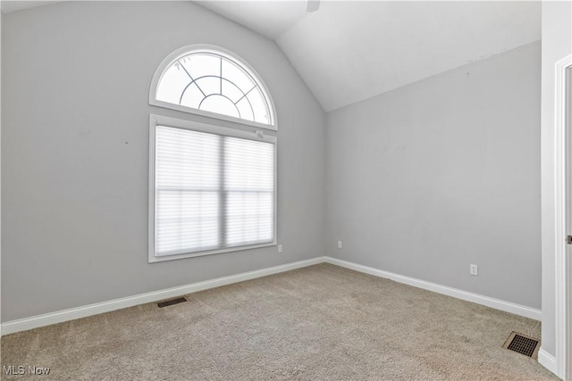 carpeted empty room with lofted ceiling, visible vents, and baseboards