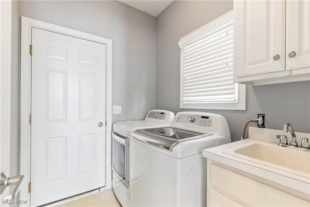 clothes washing area with cabinet space, a sink, and washing machine and clothes dryer