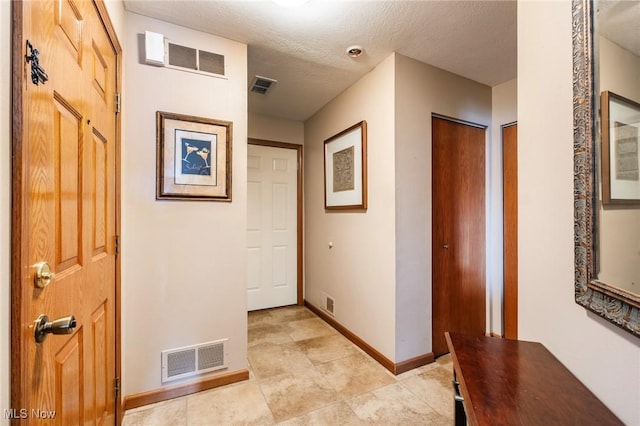 corridor featuring a textured ceiling, visible vents, and baseboards