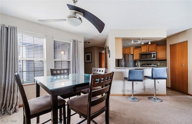 dining area featuring ceiling fan, baseboards, and light colored carpet