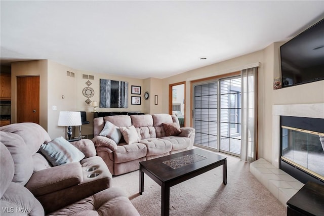 living area with light colored carpet, visible vents, and a premium fireplace