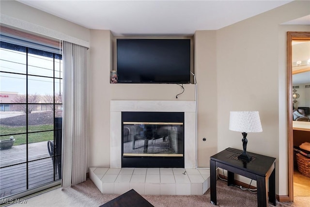 living room featuring a wealth of natural light, a tiled fireplace, and carpet