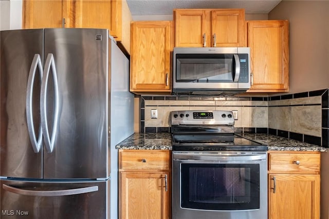 kitchen featuring dark stone countertops, stainless steel appliances, and decorative backsplash