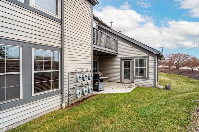 back of property with a lawn and a balcony