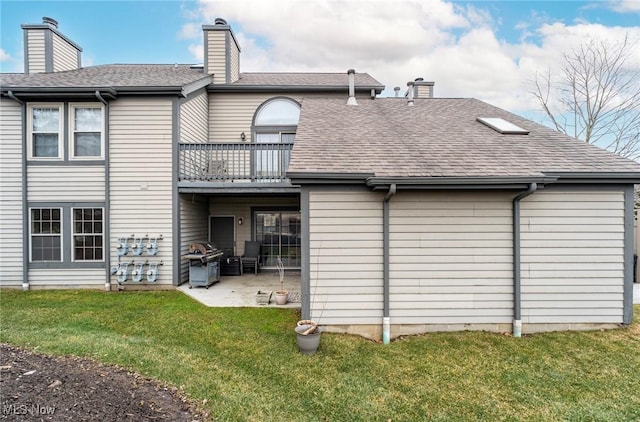back of property with a chimney, a shingled roof, a lawn, and a patio area