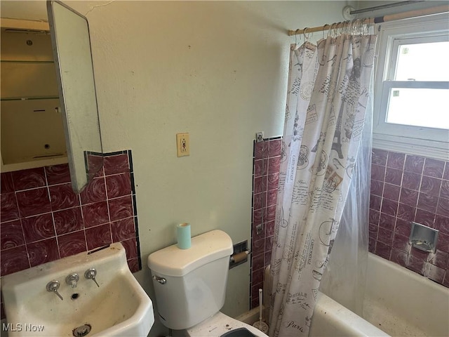 bathroom featuring toilet, shower / bath combination with curtain, and a sink