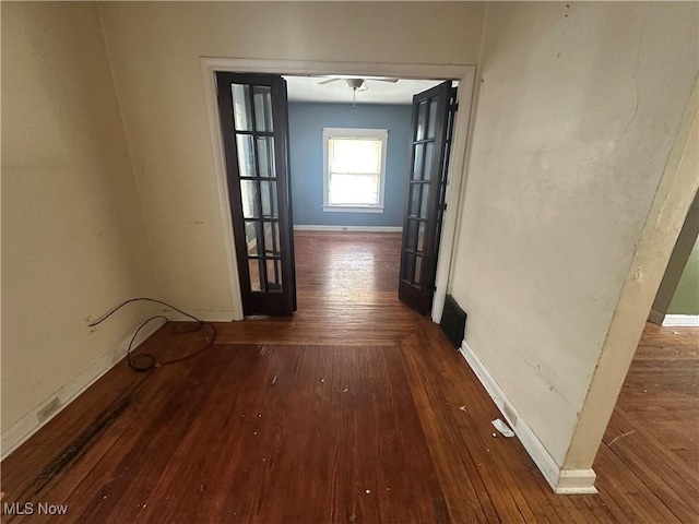 corridor featuring wood-type flooring and baseboards