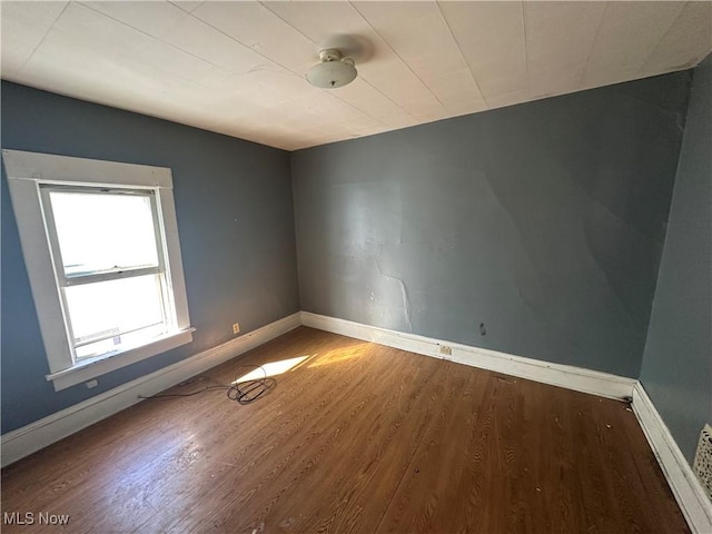 spare room featuring baseboards and wood finished floors