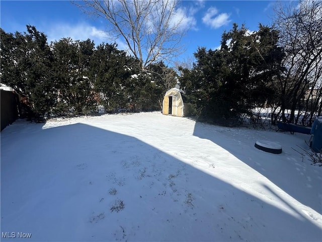 snowy yard with an outdoor structure, a storage shed, and fence