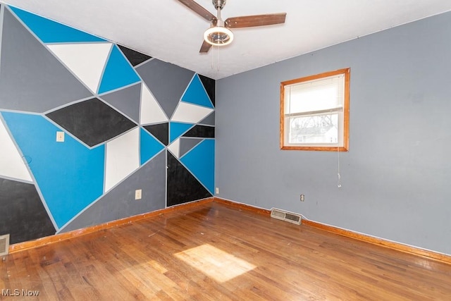 empty room with ceiling fan, visible vents, and wood finished floors