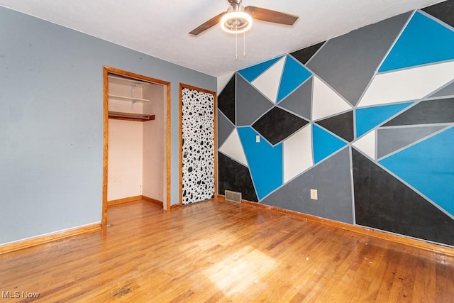 unfurnished bedroom with a ceiling fan, baseboards, visible vents, and wood finished floors