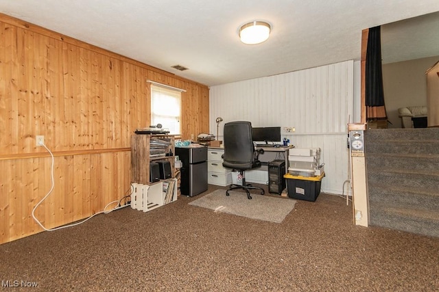 home office with carpet floors, wooden walls, and visible vents