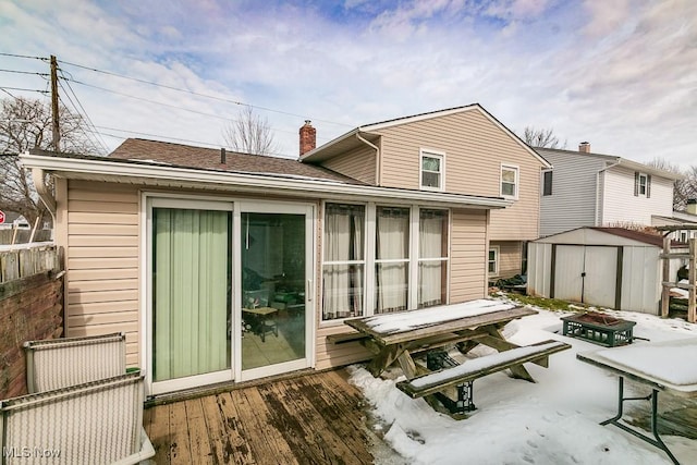 rear view of property featuring an outbuilding, a chimney, a storage shed, an outdoor fire pit, and a deck