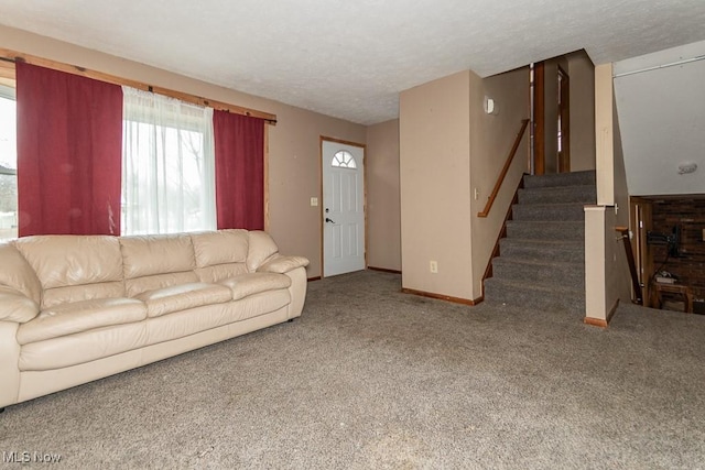 unfurnished living room featuring carpet, a textured ceiling, stairway, and baseboards