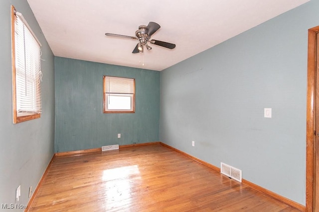 unfurnished room with baseboards, ceiling fan, visible vents, and wood finished floors