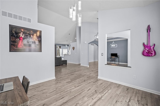 10565 Valley View Rd, Sagamore Hills, OH 44067 - unfurnished living room featuring arched walkways, wood finished floors, high vaulted ceiling, and baseboards