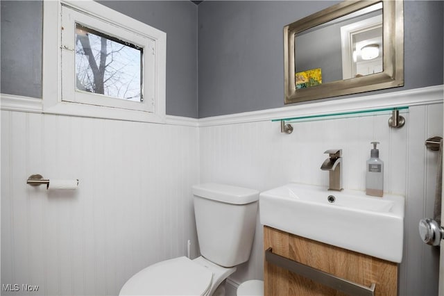 bathroom with a wainscoted wall, vanity, and toilet