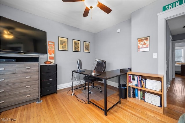 home office with baseboards, light wood-style flooring, and a ceiling fan