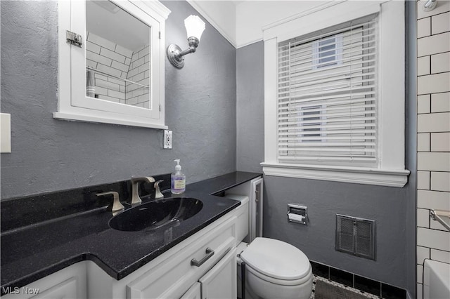 bathroom featuring toilet, a textured wall, vanity, and visible vents