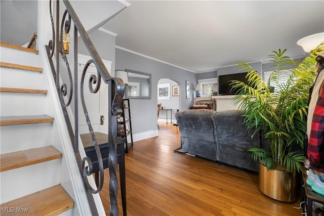 interior space featuring arched walkways, ornamental molding, wood finished floors, and baseboards