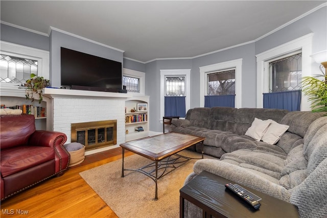 living area featuring a brick fireplace, crown molding, and wood finished floors