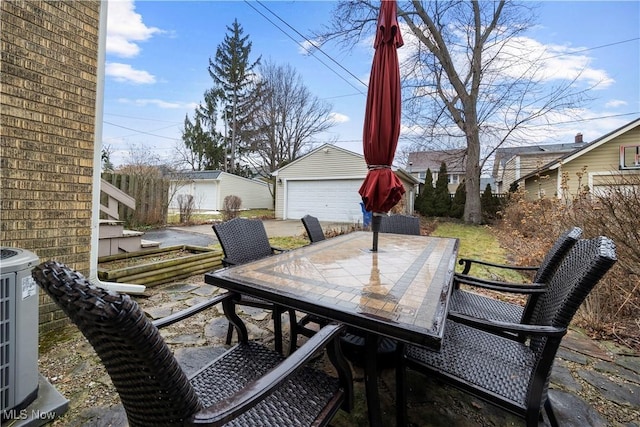 view of patio / terrace featuring cooling unit, outdoor dining area, an outdoor structure, and a detached garage