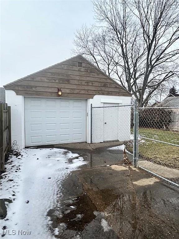 detached garage featuring driveway and fence